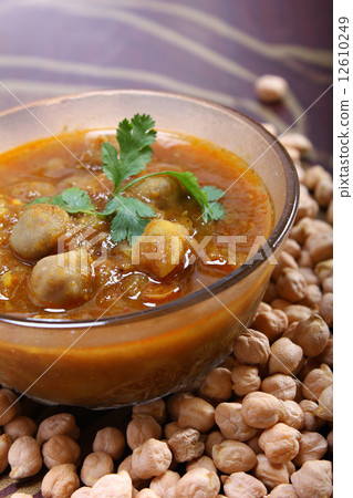 indian spicy chana masala, raw chickpeas around bowl 12610249