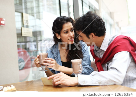 Two foreigners watching mobile at a cafe 12636384