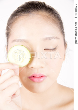 Asian young beautiful woman with flawless complexion holding cucumber slice over eye close up Asian young beautiful woman with flawless complexion holding cucumber slice over eye close up 12640877