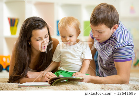 Young happy family with baby boy reading children book 12641699