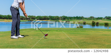 Man simulates play golf. With the stick on the green field. 12642498