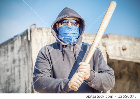 Aggressive man with a baseball bat on building background  12650073