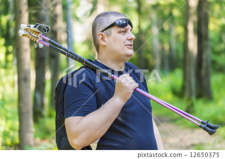 Man with walking sticks on the forest trail  12650375