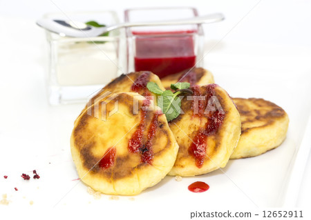 cheesecakes with sour cream and jam on table in restaurant 12652911