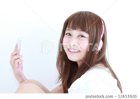 一個半長直的年輕女子，聽聽音樂 12653920