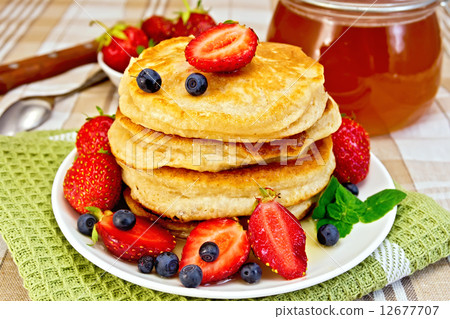 Flapjacks with strawberries and blueberries on napkin 12677707