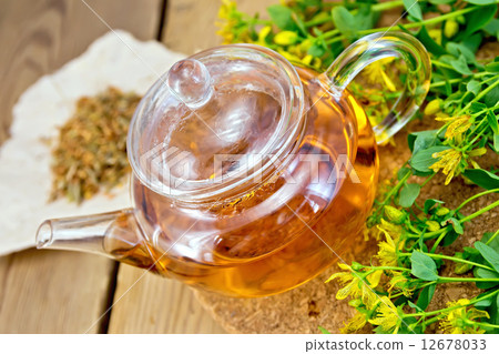 Tea with fresh and dry tutsan in glass teapo on board 12678033