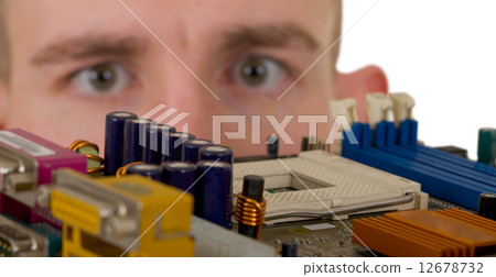Man examines an electronic circuit Man examines an electronic circuit 12678732