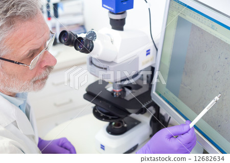 Senior scientist  microscoping in lab. 12682634