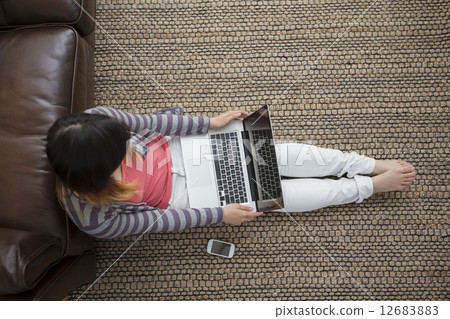 Above view Chinese woman sitting on floor with laptop. 12683883