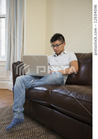 Asian man using Laptop at home in the lounge. Asian man using Laptop at home in the lounge. 12684096