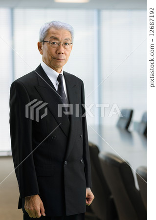 Senior CEO standing in the executive meeting room Senior CEO standing in the executive meeting room 12687192