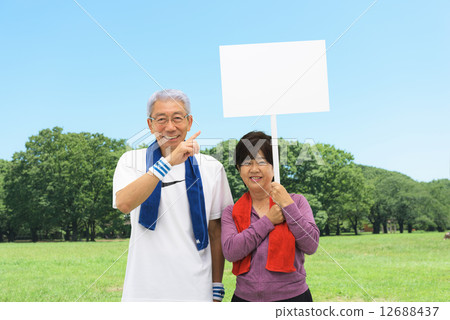 Senior couple having placards in a blue sky park 12688437