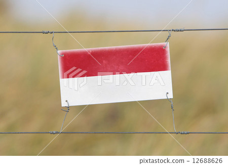 Border fence - Old plastic sign with a flag Border fence - Old plastic sign with a flag 12688626