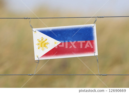 Border fence - Old plastic sign with a flag 12690669