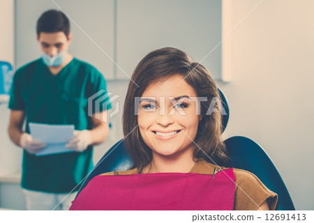 Man dentist reading woman patient's card 12691413