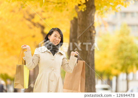 拿著在兩隻手上的婦女一個購物袋 12694478