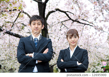Men and women of suits in front of cherry blossoms 12695900