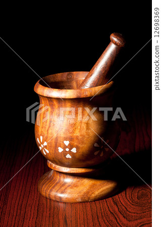 Wooden mortar and pestle on dark 12698369