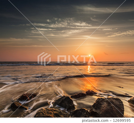 Waves and rocks on beach of sunset 12699595