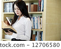Beautiful female is reading a book in the library 12706580