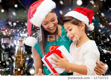 happy mother and girl in santa hats with gift box 12710723
