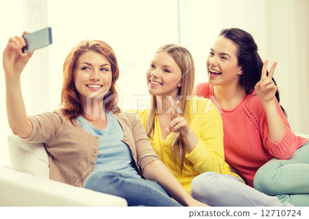 smiling teenage girls with smartphone at home 12710724