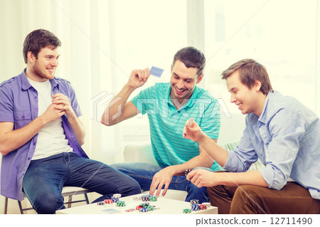 happy three male friends playing poker at home happy three male friends playing poker at home 12711490