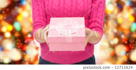close up of woman in pink sweater holding gift box 12711624