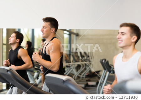 smiling men exercising on treadmill in gym smiling men exercising on treadmill in gym 12711930
