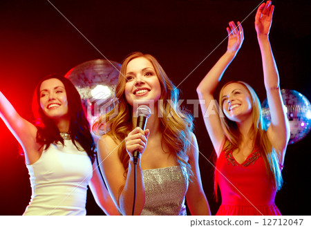 three smiling women dancing and singing karaoke 12712047