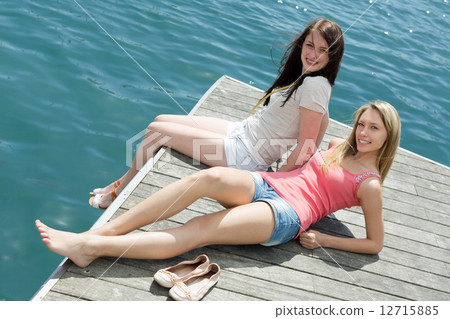 Two young girls in casual clothes sunbathing Two young girls in casual clothes sunbathing 12715885