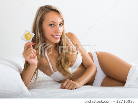 Sexy woman holding condom in bed 12716053