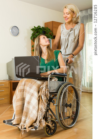 Social worker and invalid with laptop 12716285