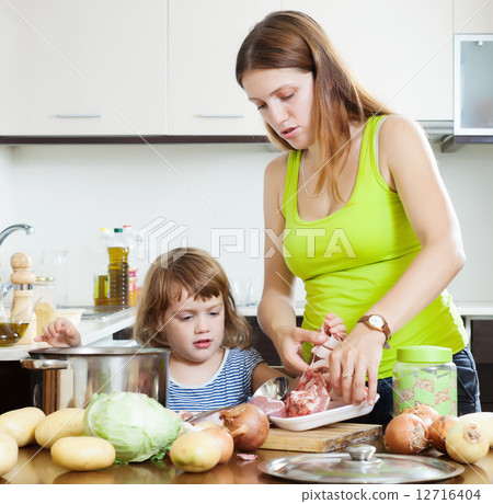 woman with baby cooking with meat 12716404