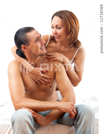 Middle-aged couple kissing and playing on white sheet in bed 12716568