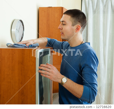 Man cleaning shelf with rag and cleanse in living room Man cleaning shelf with rag and cleanse in living room 12716620