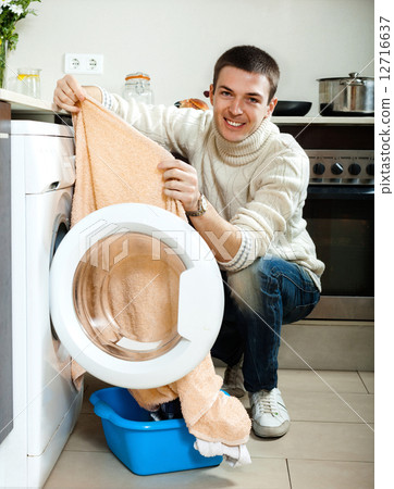 man putting clothes in to washing machine man putting clothes in to washing machine 12716637