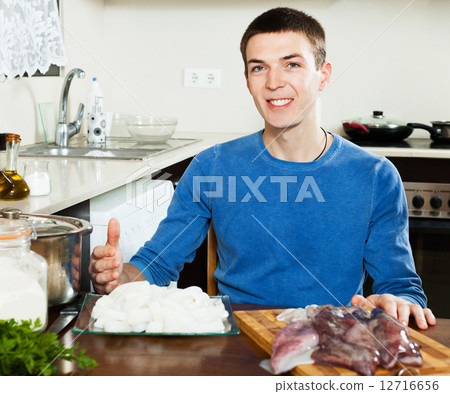 Man cooking raw squid 12716656