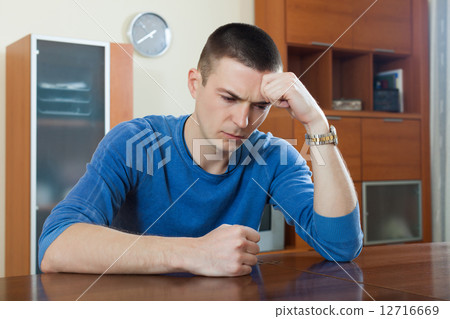 Young guy with phone at table in home 12716669