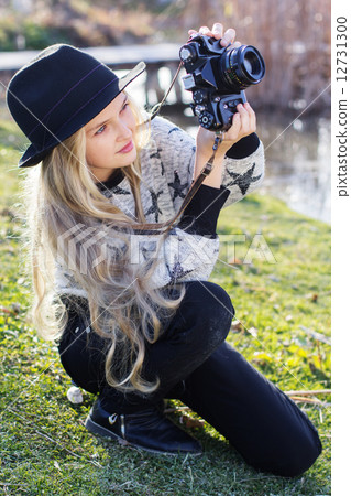 Cute little girl is resting near lake with camera 12731300