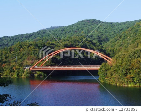 A crescent moon bridge over a dam lake A crescent moon bridge over a dam lake 12733855