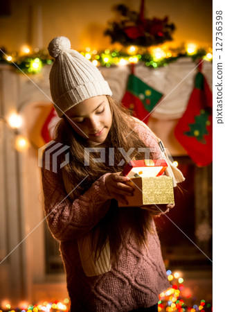 little girl wearing sweater looking in gift box at Christmas eve little girl wearing sweater looking in gift box at Christmas eve 12736398