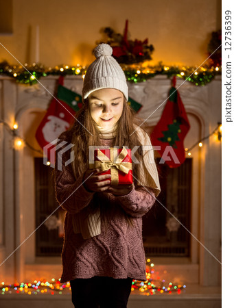 girl in wool sweater and hat looking inside of glowing present b girl in wool sweater and hat looking inside of glowing present b 12736399