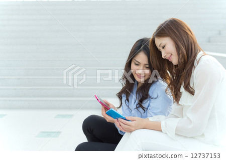 兩個分享智能手機的女性 12737153