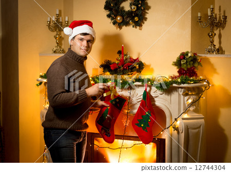 smiling man posing with gift box at decorated fireplace smiling man posing with gift box at decorated fireplace 12744304