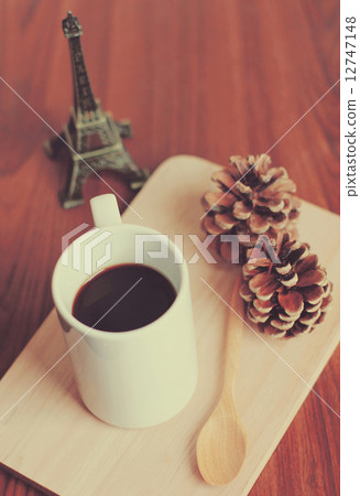 Black coffee and spoon on wooden tray with pine cone, retro filt 12747148