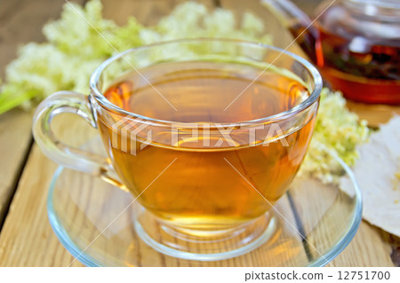 Tea from meadowsweet in glass cup and teapot on board 12751700