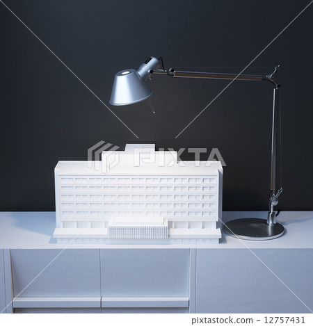 Model Of Building Under The Lamp On The Desk 12757431