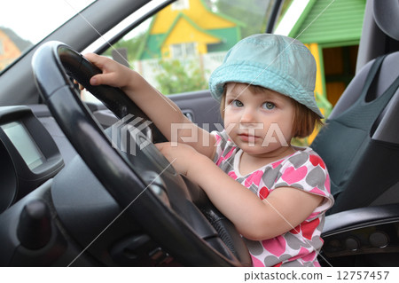 Cute little girl is sitting behind the wheel of a car Cute little girl is sitting behind the wheel of a car 12757457